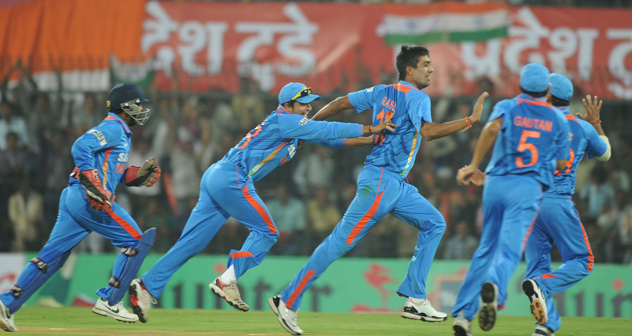 Rahul Sharma is mobbed by his team-mates after taking a wicket