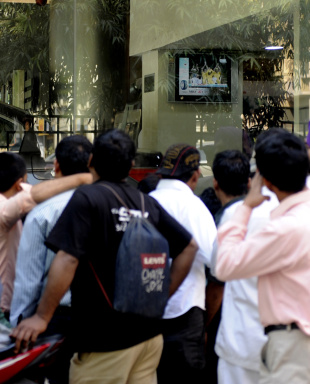 Bystanders gather around a shop window to watch a match, Delhi, March 24, 2011