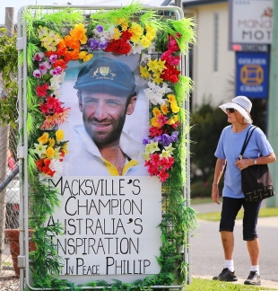 A woman walks past a tribute to Phillip Hughes outside a used-cars dealership, Macksville, December 2, 2014